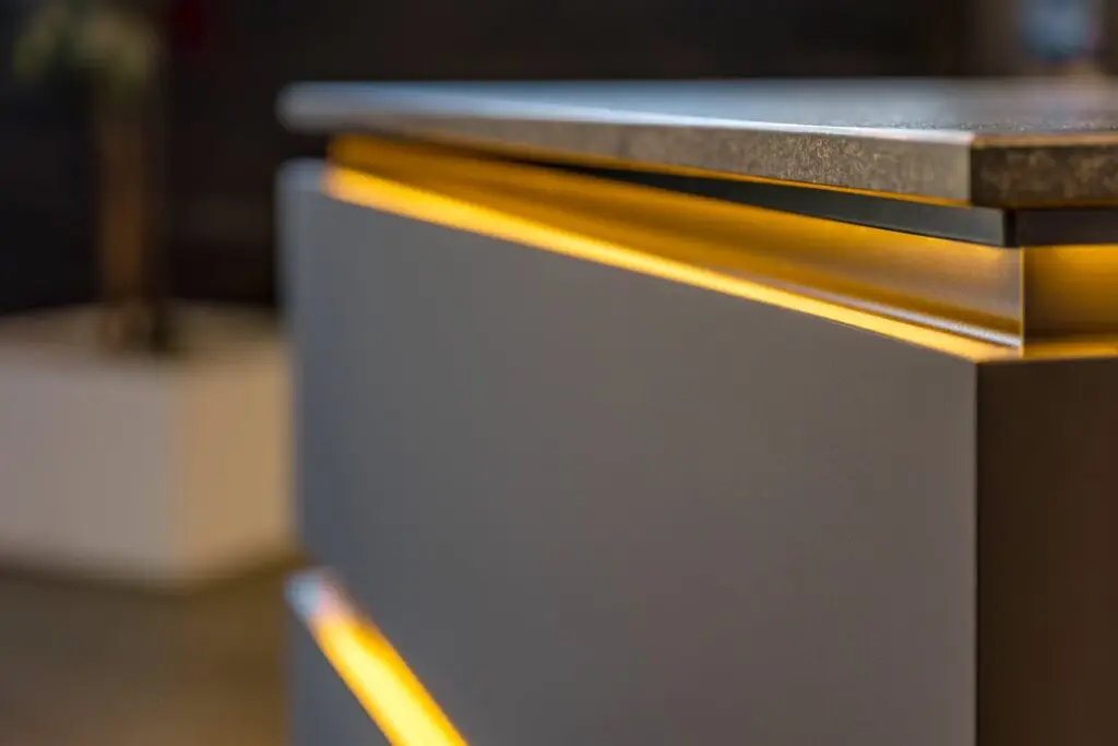 Perfil LED de luz cálida bajo el canto de una encimera de cocina